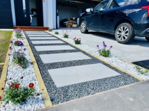 Paver path along driveway with gravel and flowering plants