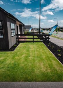 New lawn with garden bed beside a black fence