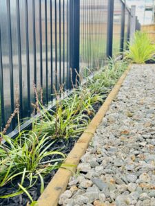 Planted gravel edge beside a fence